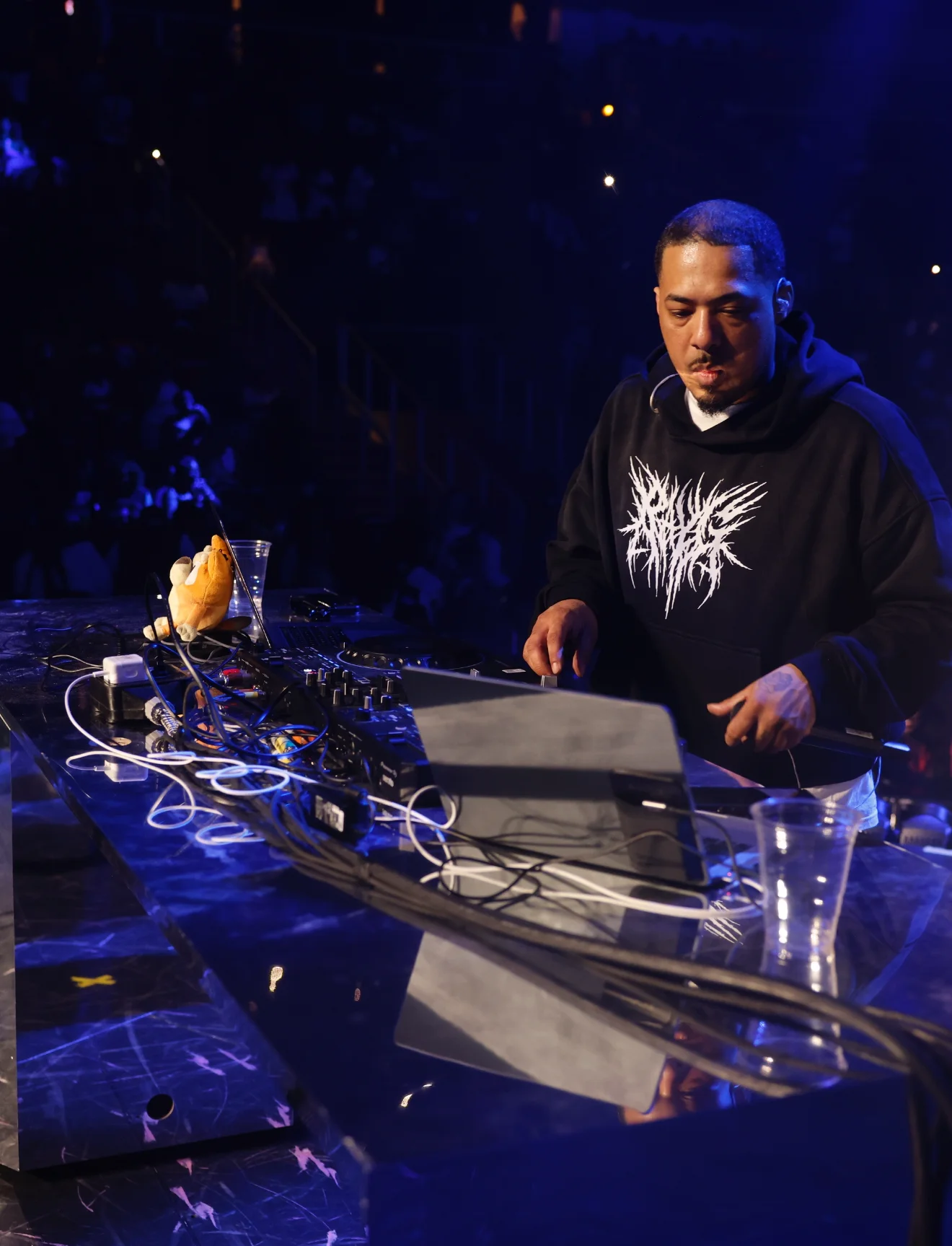 A DJ at the decks with blue lights overhead.